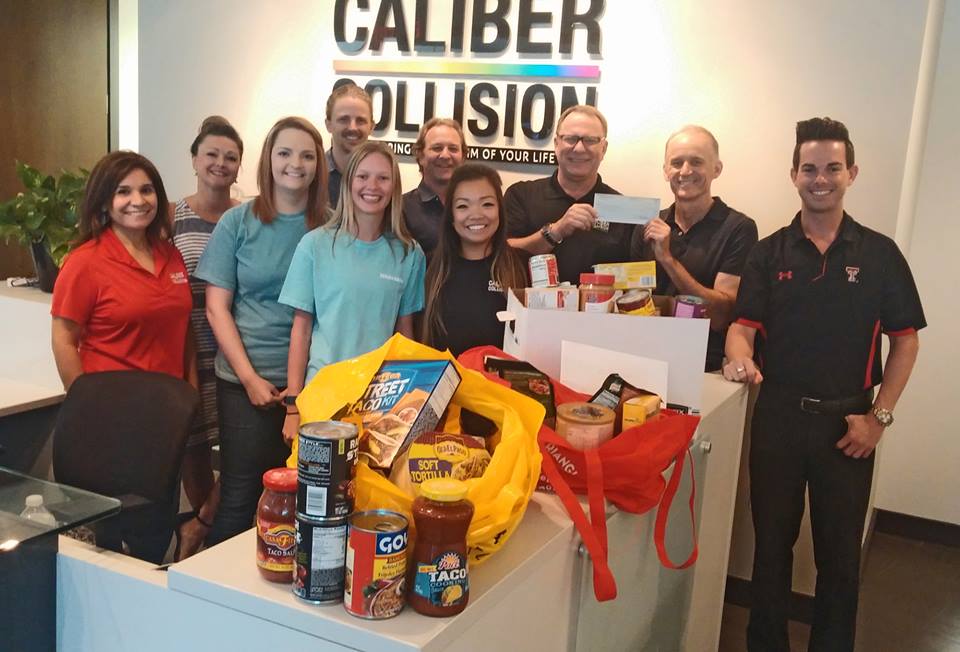 Caliber Collision and Johnson and Sekin staff pose with food drive items and a donation check.
